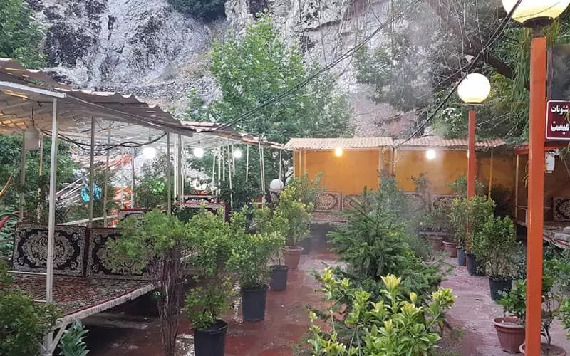 رستورانی با تخت هایی در فضای باز و بین گل و گیاه