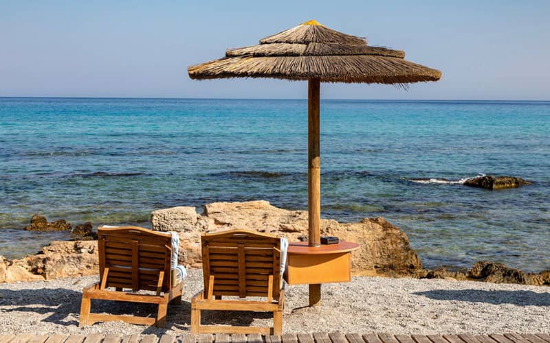 دو صندلی راحتی کنار سایه بانی در ساحل
