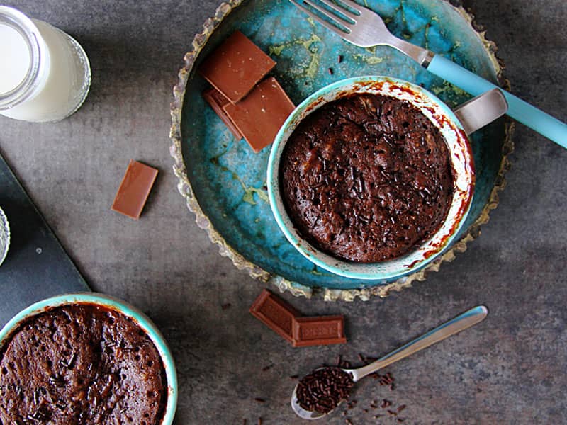 دو فنجان کیک شکلاتی در کنار تکه های شکلات تخته ای