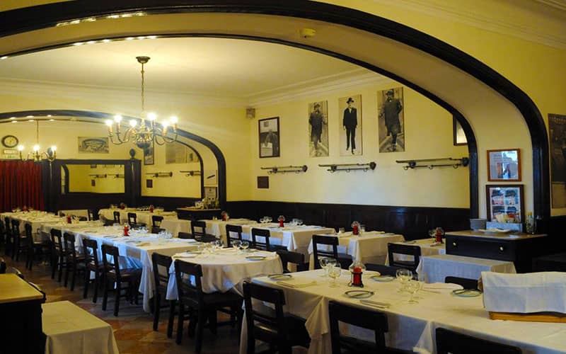 رستورانی بزرگ با رومیزی های سفید و صندلی های قهوه ای