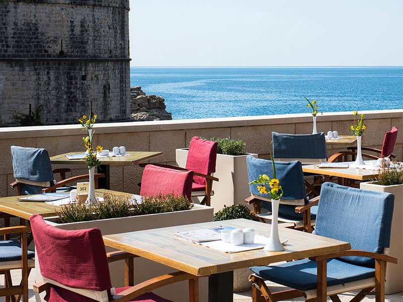 رستورانی با صندلی های آبی و صورتی در کنار دریا