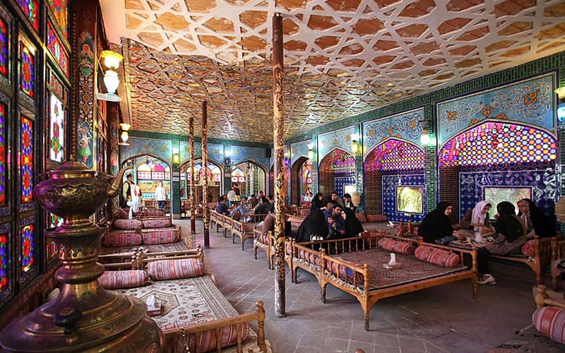 رستورانی سنتی با تخت های چوبی و پنجره های رنگی