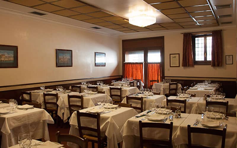 رستورانی ساده با رومیزی های سفید و نور کم
