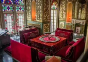 استراحتگاه کاخ صاحبقرانیه با میز و پشتی‌های قرمز