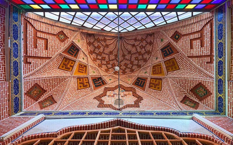 سقف مسجدی با پنجره های رنگی و آجرکاری و اسامی علی و محمد