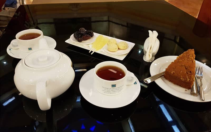 دو فنجان چای و قوری چای و یک بشقاب کیک