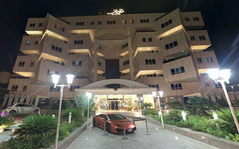 عکس هتل ایران در طول شب با خودرویی لوکس در ورودی هتل