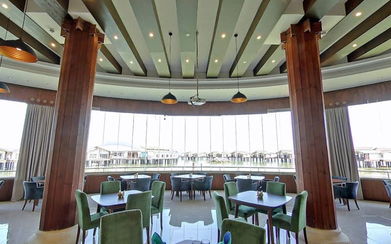 رستورانی با دو ستون بزرگ چوبی و پنجره های شیشه ای قدی رو به دریا