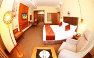 اتاق هتل با تخت دو نفره بزرگ و مبل یک نفره و میز کار و تلویزیون