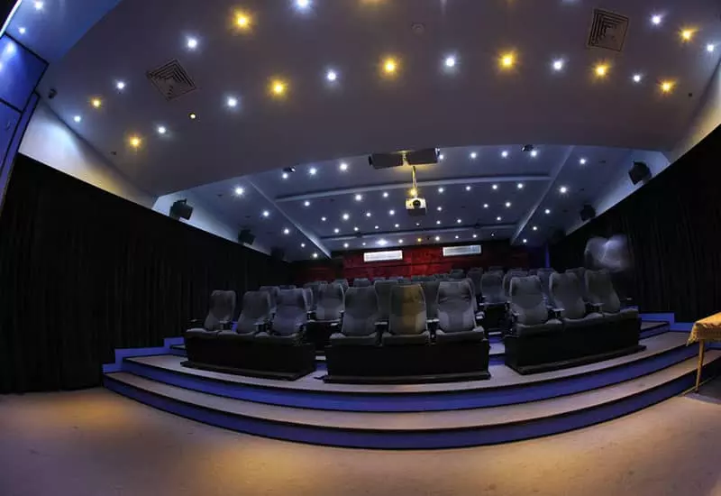 سالن سینمایی با صندلی های طوسی رنگ و نورپردازی آبی و زرد