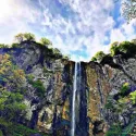 آبشار لاتون در میان صخره‌های بلند و آسمان زیبا