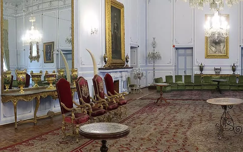 سالن بزرگی با صندلی های قرمز و سبز و دو عاج بزرگ جلوی آینه