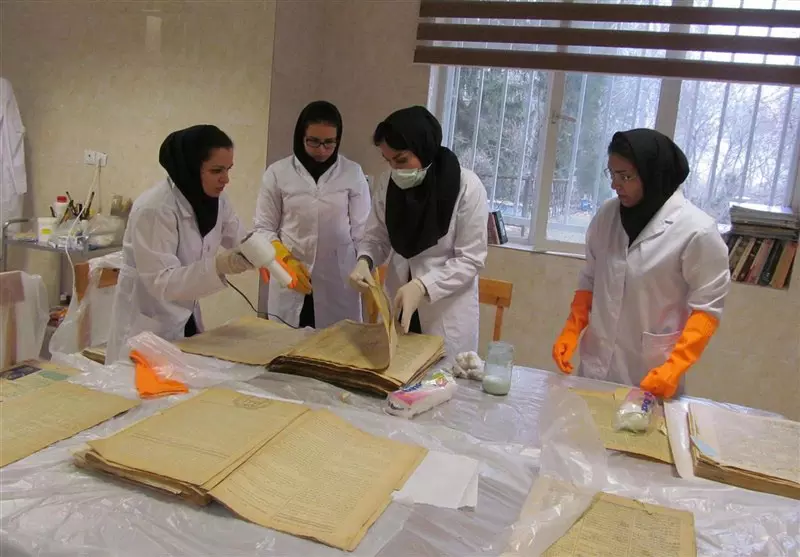محققان جوان مشغول بررسی نسخ قدیمی و خطی در کارگاه مرمت سعد آباد