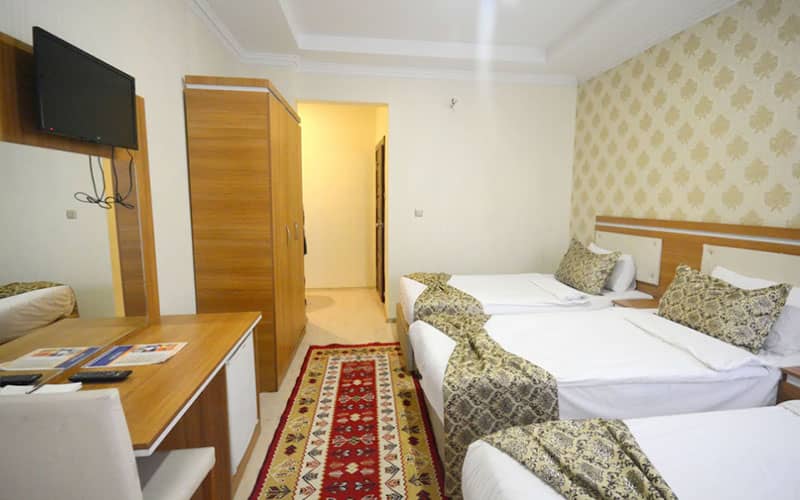اتاق سه تخته هتل با یک کمد چوبی و میز آرایش