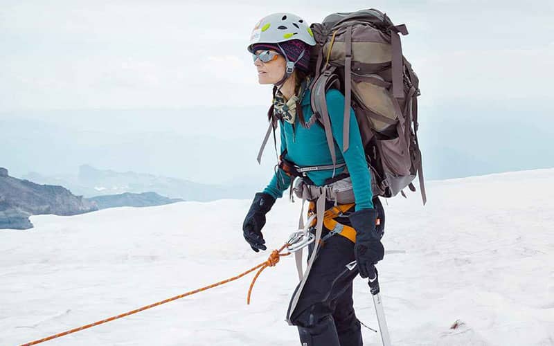 زن کوهنوردی در حال صعود در هوای برفی