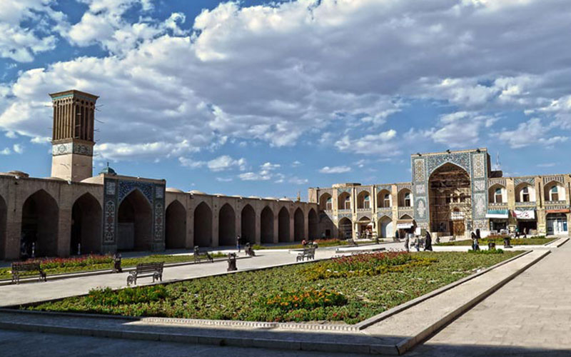 میدانی بزرگ با سازه ای تاریخی در اطرافش در کرمان