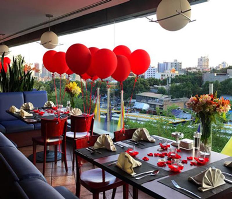 میز تزئین شده تولد با بادکنک های قرمز در رستوران زنبق آبی