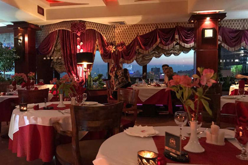 میزهای داخل رستوران نارنجستان با تزئینات قرمز