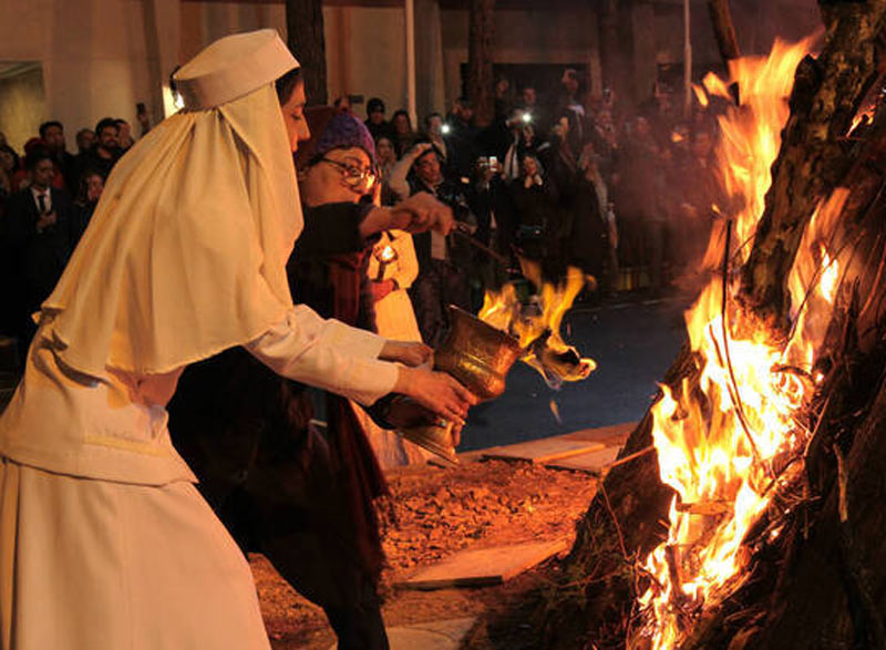 موبد زرتشتی و دختر سفیدپوش در حال روشن کردن آتش جشن سده