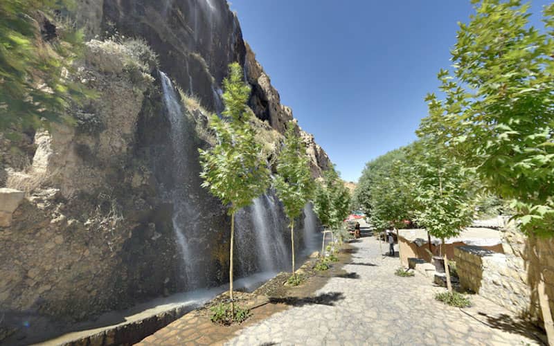 آبشاری پرآب در کنار درختان سبز