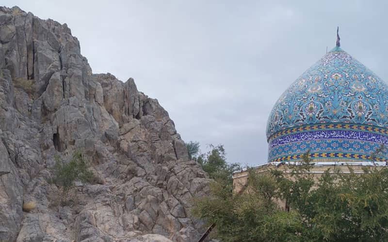 گنبد فیروزه ای امامزاده در کنار کوه