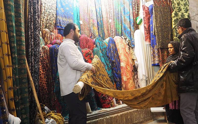 دو نفر در حال خرید پارچه در بازار کرمان