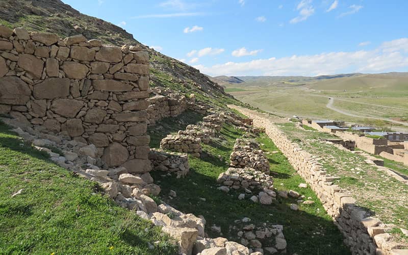 تپه ای سرسبز با بقایی دیواری سنگی