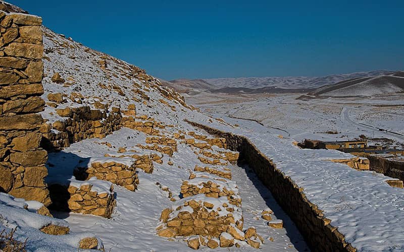 بقایای دیوارهای سنگی زیر برف زمستانی