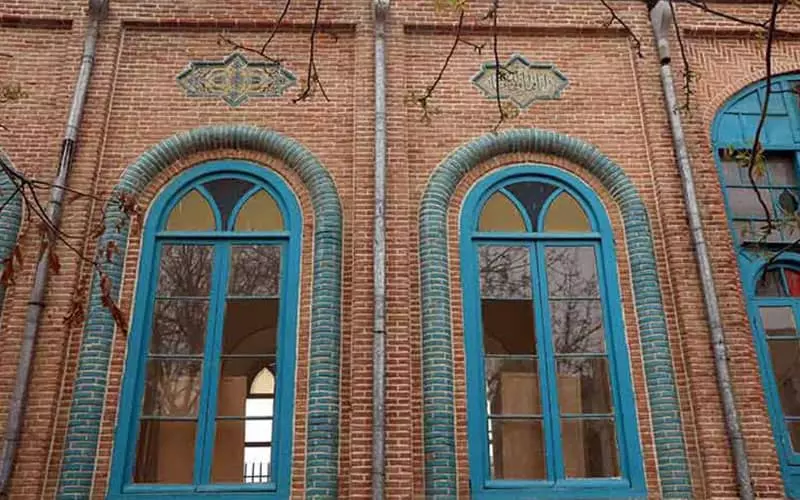 خانه ای تاریخی با دیوارهای آجری و پنجره های آبی رنگ