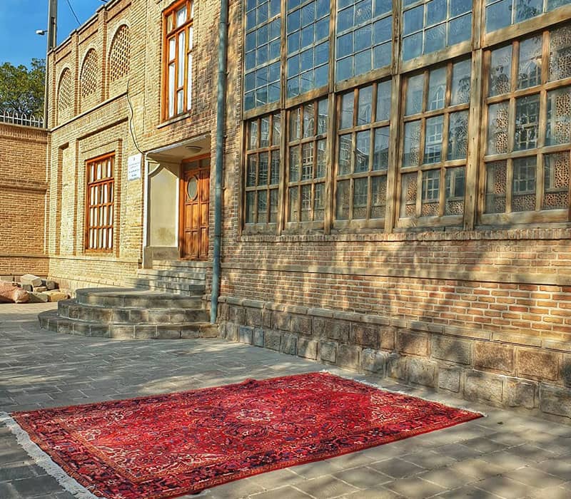 قالیچه ای قرمزرنگ در مقابل ساختمانی تاریخی