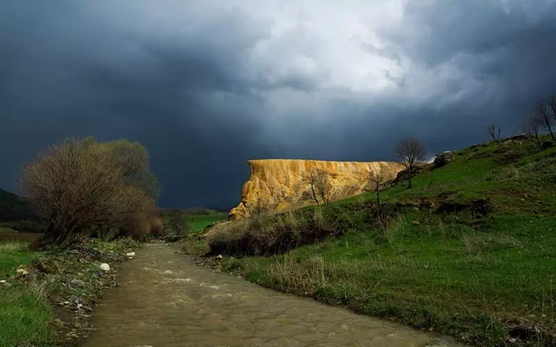 کوهی زردرنگ در منطقه ای سرسبز و کنار رودخانه