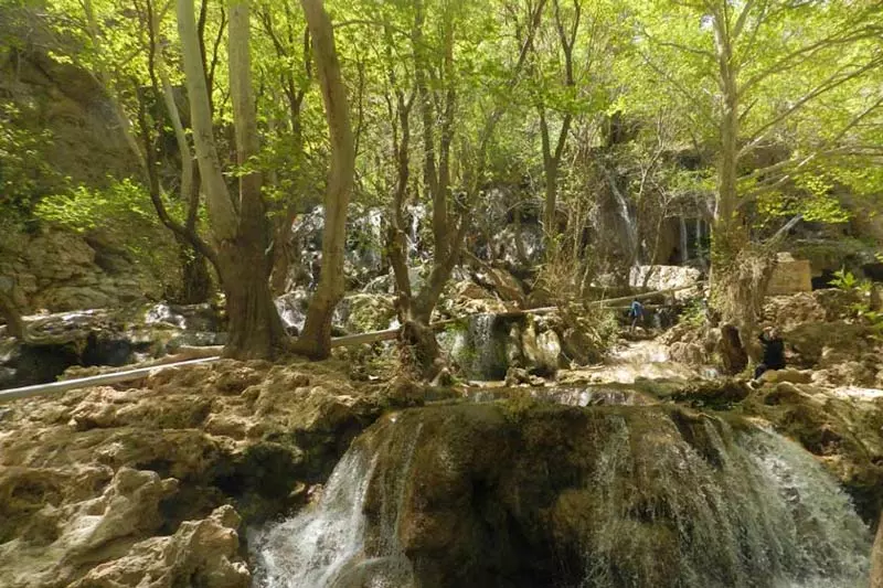 آبشارهای تنگ بستانک در میان درختان سبز و صخره ها