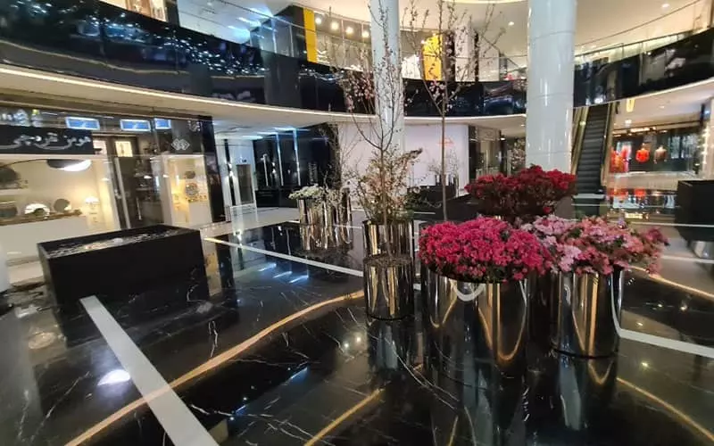 طبقه همکف مرکز خرید سام با گلدان مصنوعی بزرگی در وسط آن