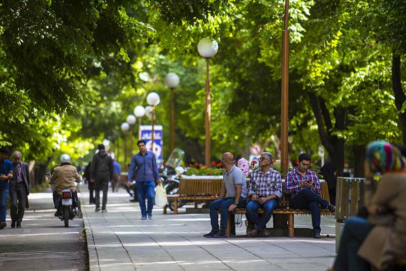 مردم نشسته روی نیمکت‌های خیابان چهارباغ عباسی 
