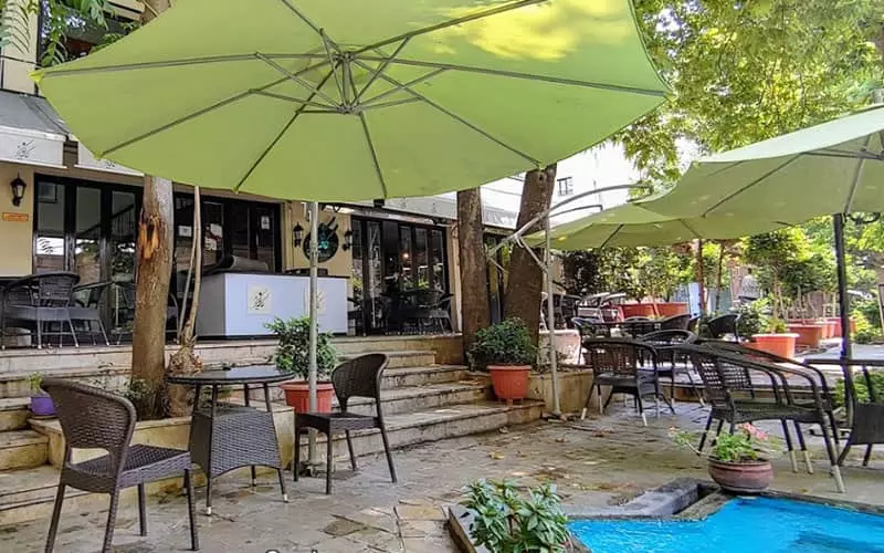 فضای روباز کافه باغ کاریز همراه با سایبان سبزرنگ