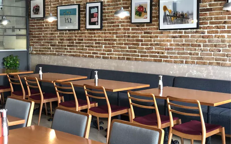 کافه لانجین با میز و صندلی های چوبی و دیوار آجری