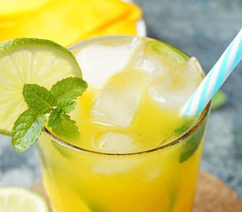 یک لیوان نوشیدنی زردرنگ با تزیین نعناع و لیموترش