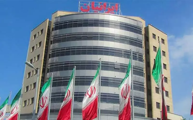 ساختمان شیشه ای مرکز خرید ایرانیان با پرچم های ایران در مقابلش