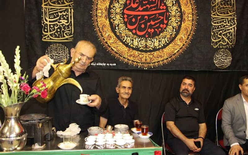 پیرمردی در حال ریختن چای و قهوه در تکیه امام حسین