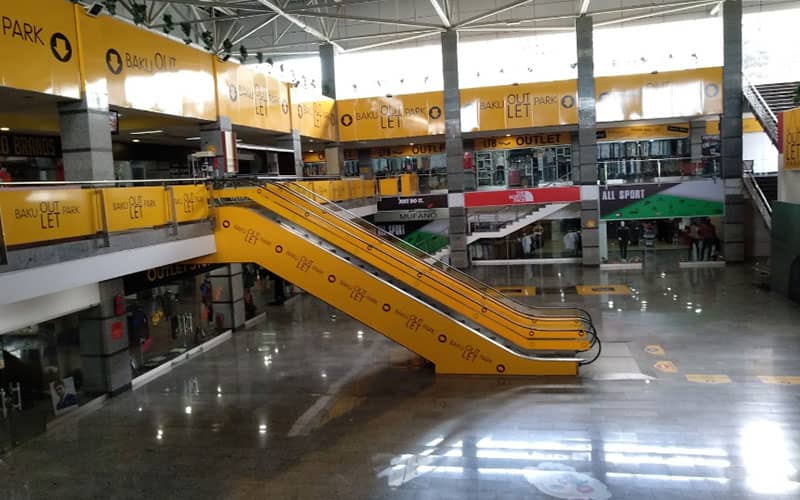 فضای داخلی مرکز خریدی بزرگ با پله برقی زردرنگ