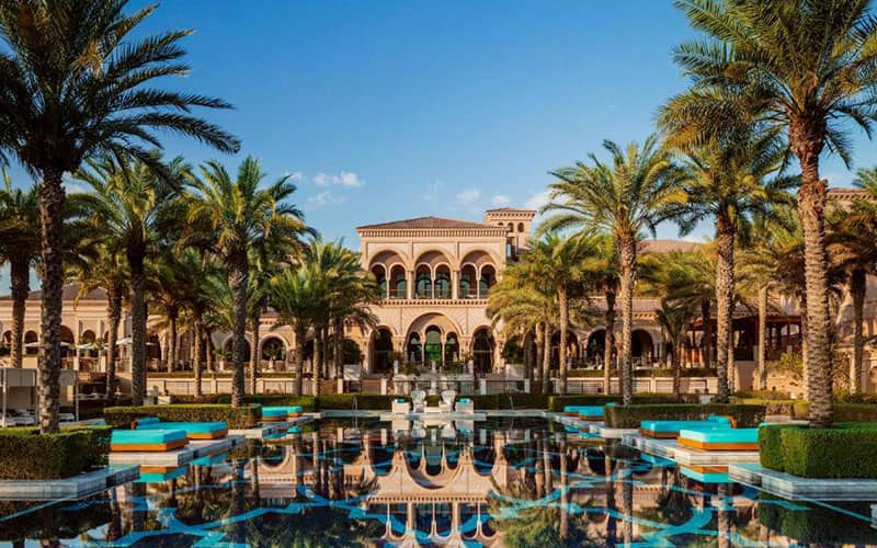هتلی با معماری عربی و سنگفرش سیاه و آبی و درختان نخل