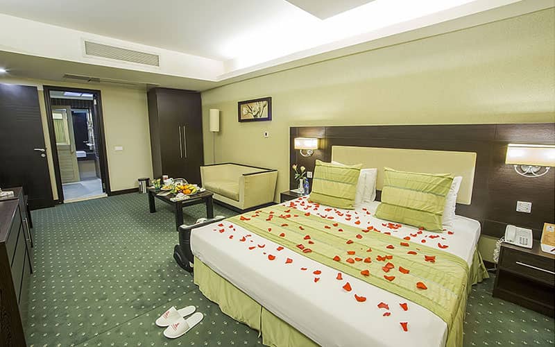 تخت دو نفره با تزیین گل در اتاق بزرگ هتل
