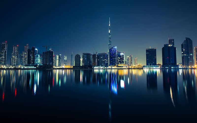 ساختمان های مرتفع دبی در شب و تصویر آن‌ها در آب دریاچه