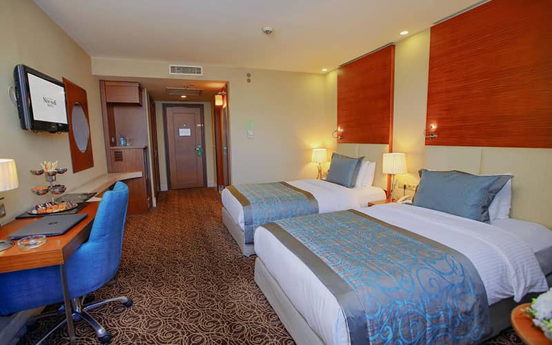 دو تخت دونفره با میز تحریر و تم آبی در اتاق هتل نیوپارک