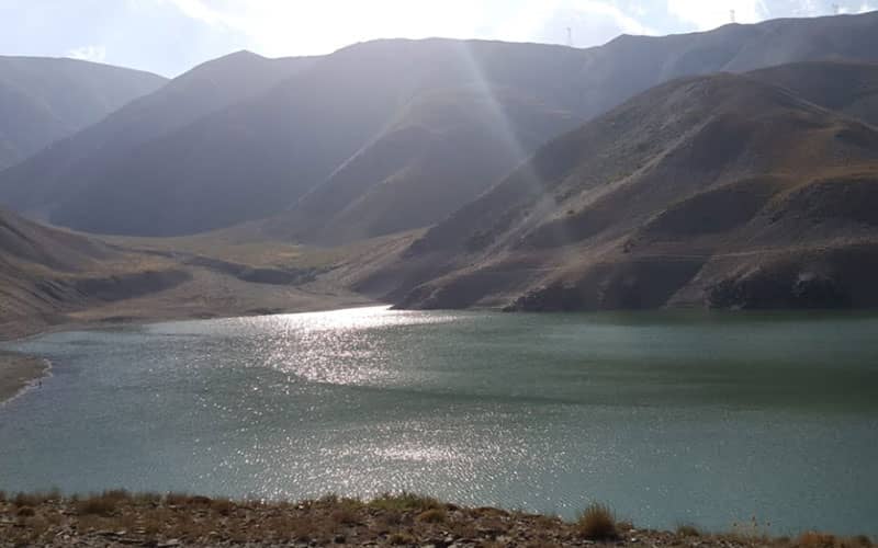 دریاچه ای در میان کوه ها و زیر نور خورشید