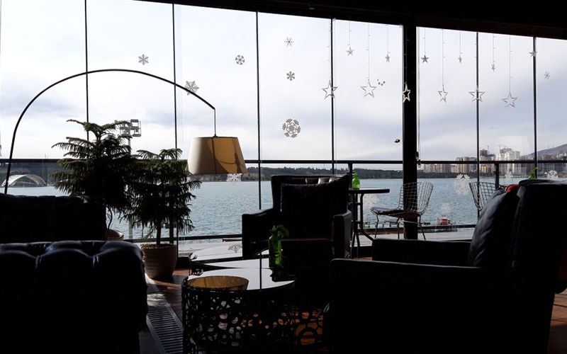 رستورانی با صندلی های چرمی و پنجره های قدی رو به دریاچه