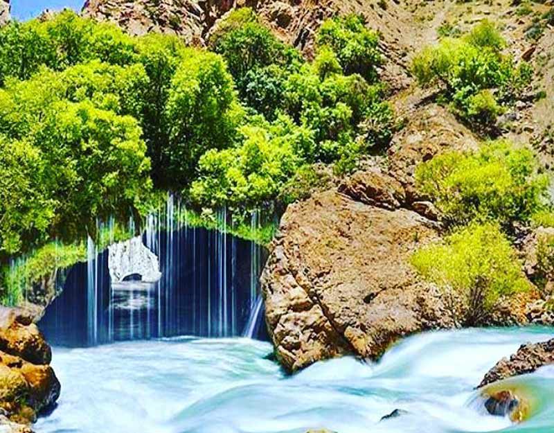 آبشار آب ملخ میان صخره های کوهستانی از نمای روبه رو