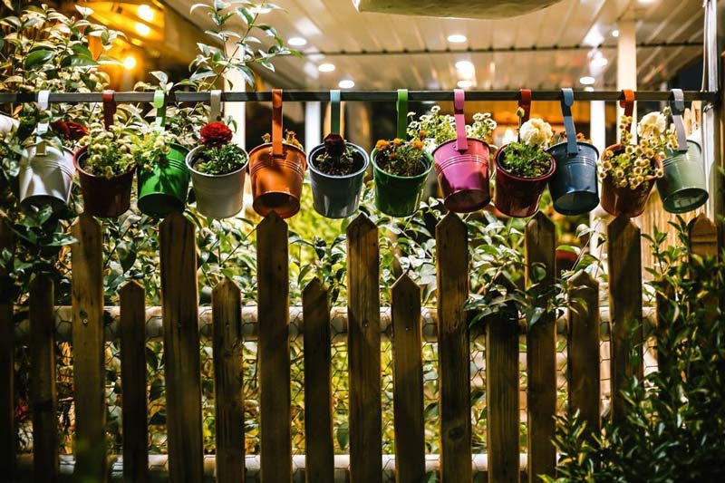 گلدان های رنگی روی نرده های چوبی در ورودی رستوران بیستون فرحزاد