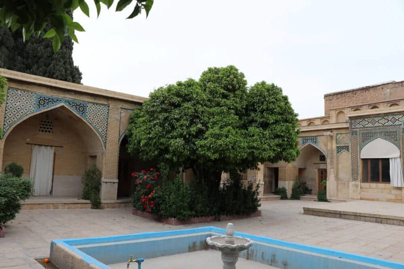 حوض آبی و درخت سبز در حیاط مدرسه منصوریه شیراز