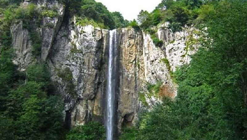 آبشار نوجان میان صخره های کوهستان از نمای دور